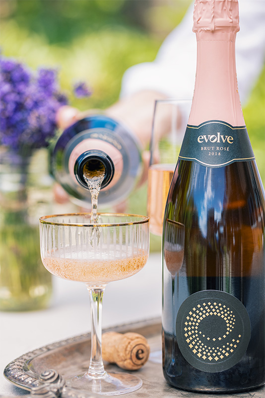 Evolve Brut Rosé being poured into a gold rimmed coupe